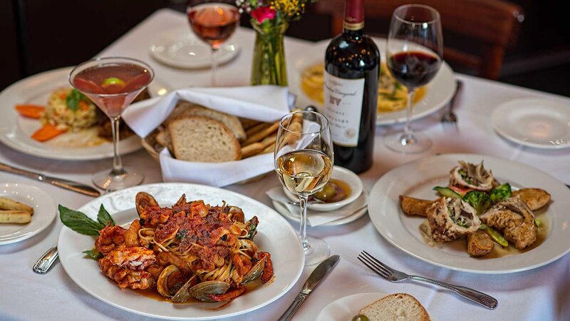 Set table with many entrees and drinks with a basket of bread