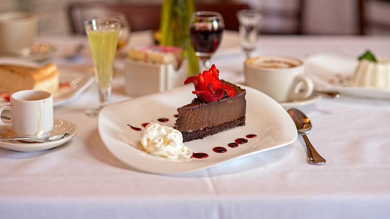 Chocoalate cake dessert topped with a flower and a side of cream