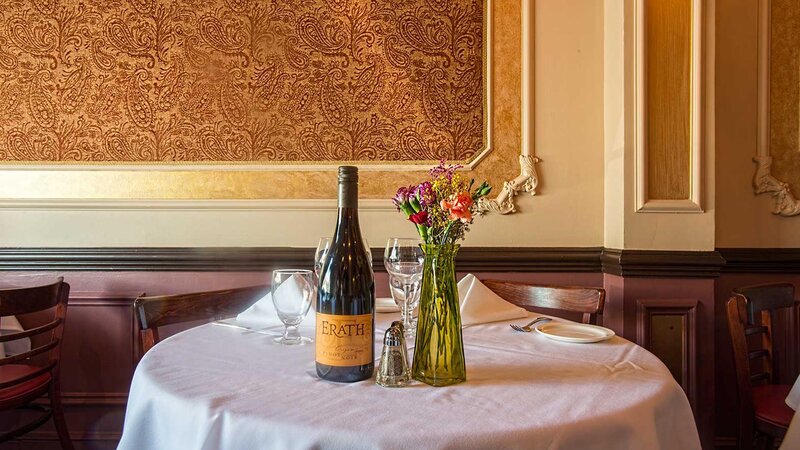 A wine bottle and flower vase on a set table